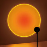 360-degree rotating LED sunset projection lamp creating warm ambient lighting in a modern bedroom and living room decor setting