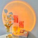 360-degree rotating LED sunset projection lamp creating warm ambient lighting in a modern bedroom and living room decor setting